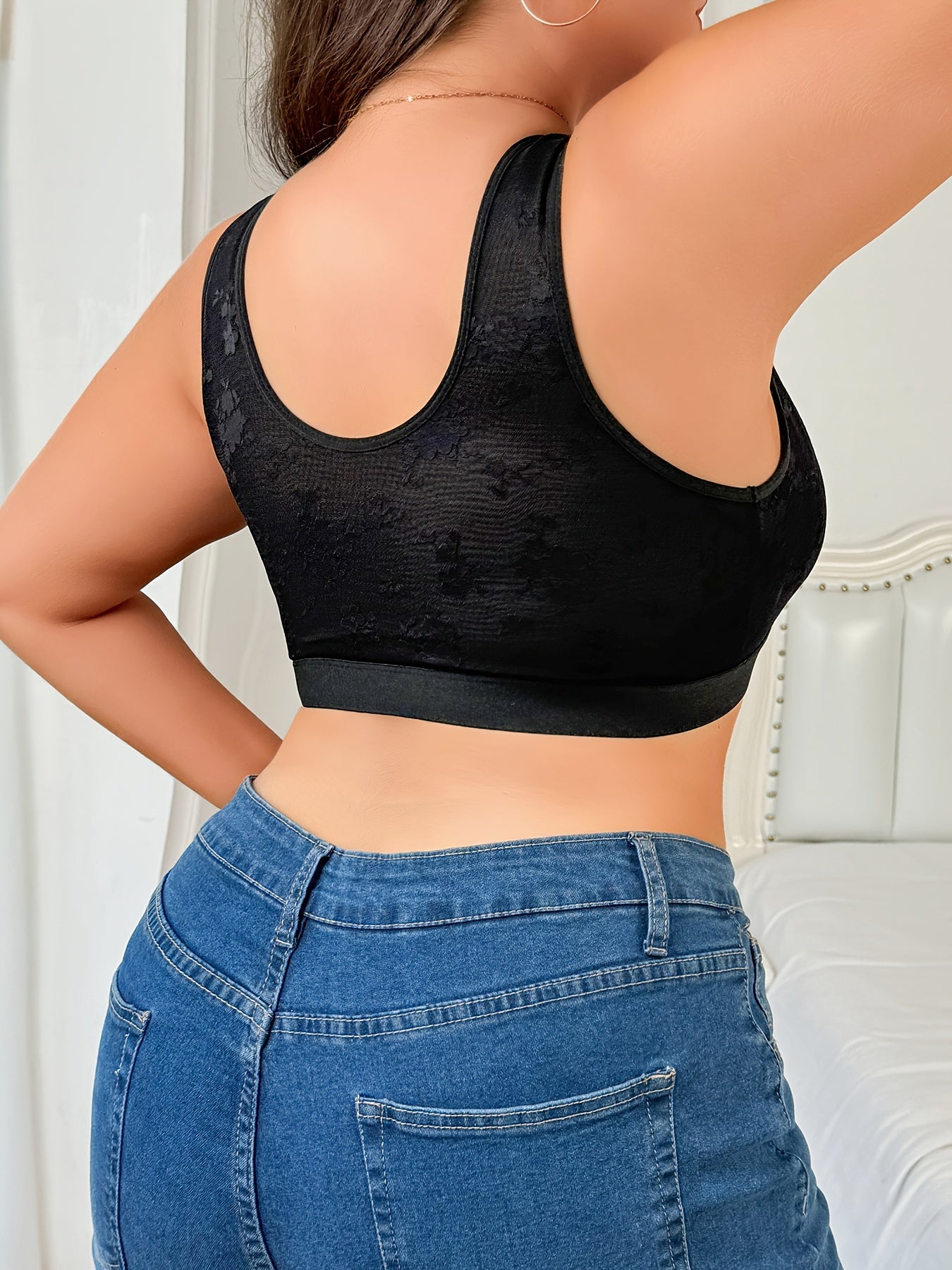 Lace-trimmed shapewear top for women with front closure. Medium support, non-padded. Polyester and elastane blend with a floral pattern in sleek black. Hand washable. Fashionable and