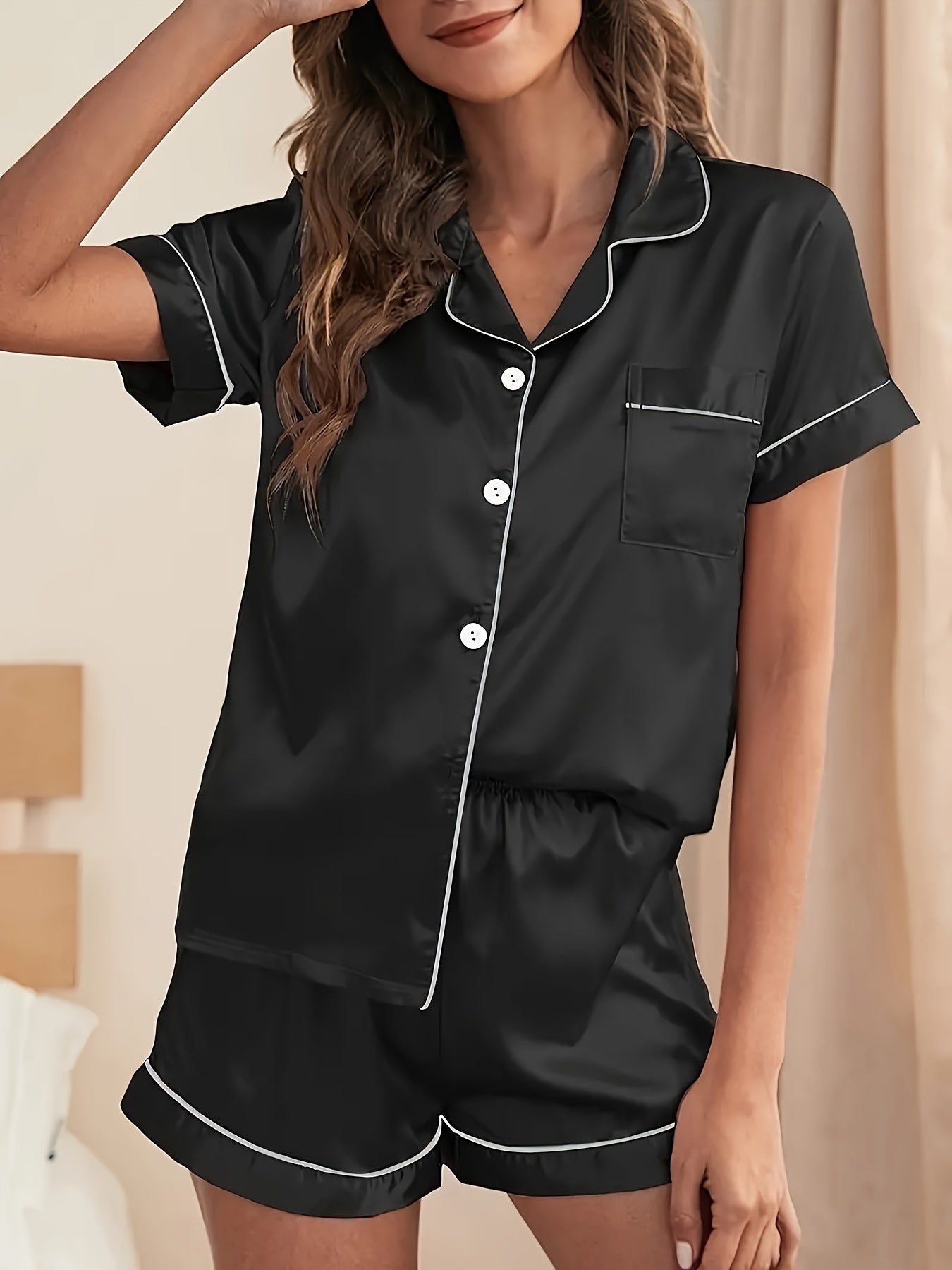 Women's satin pajama set in solid color with short-sleeved lapel top and elastic waistband shorts.