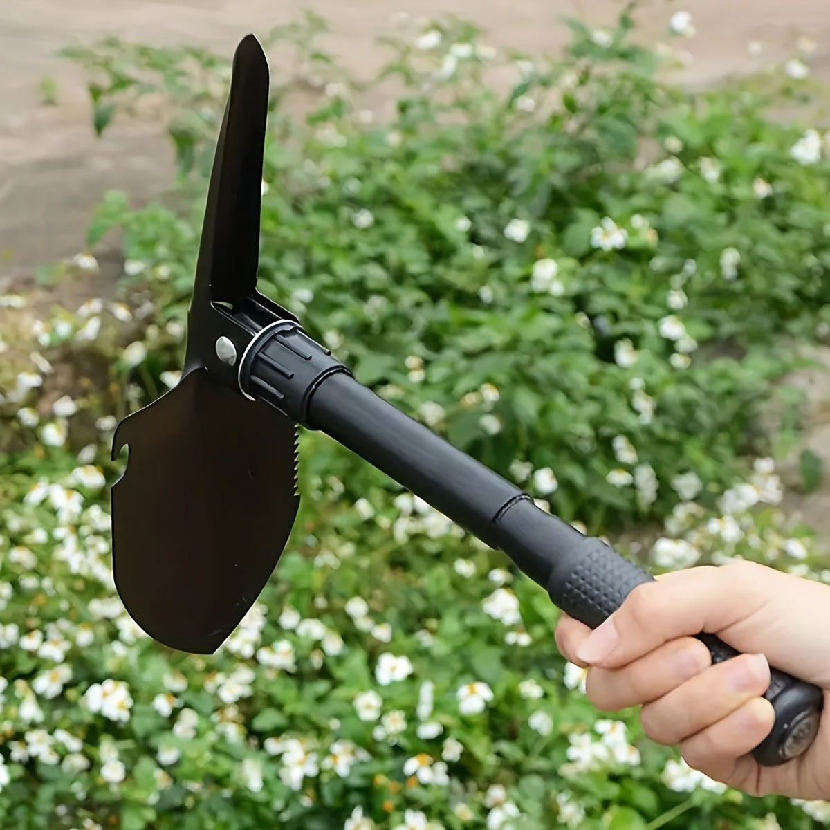 Stainless steel folding shovel with saw, pickaxe, bottle opener, and storage bag for camping and outdoor survival.