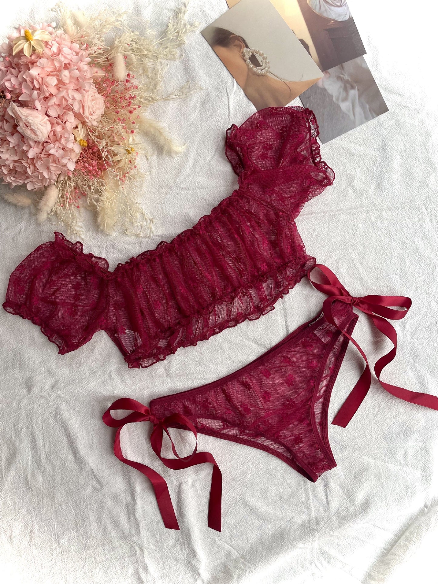 Red lace lingerie set with off-shoulder bra and low-rise panties for women.