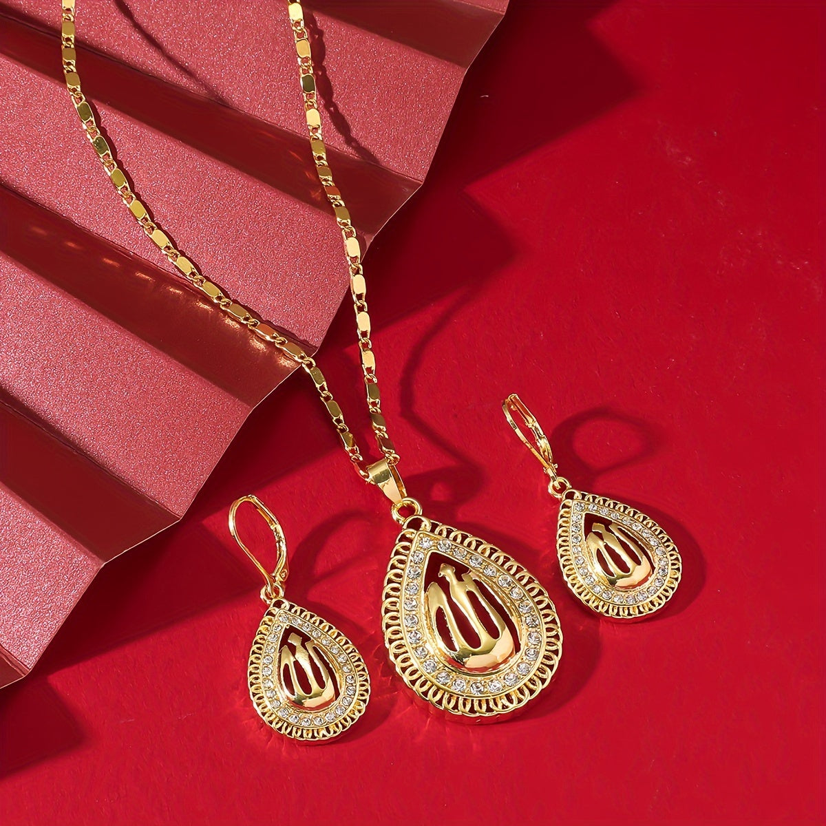 A jewelry set featuring a pendant necklace and earrings in Middle Eastern luxury style, with a golden water drop shape and interlaced lines design featuring a hollow Allah pattern.