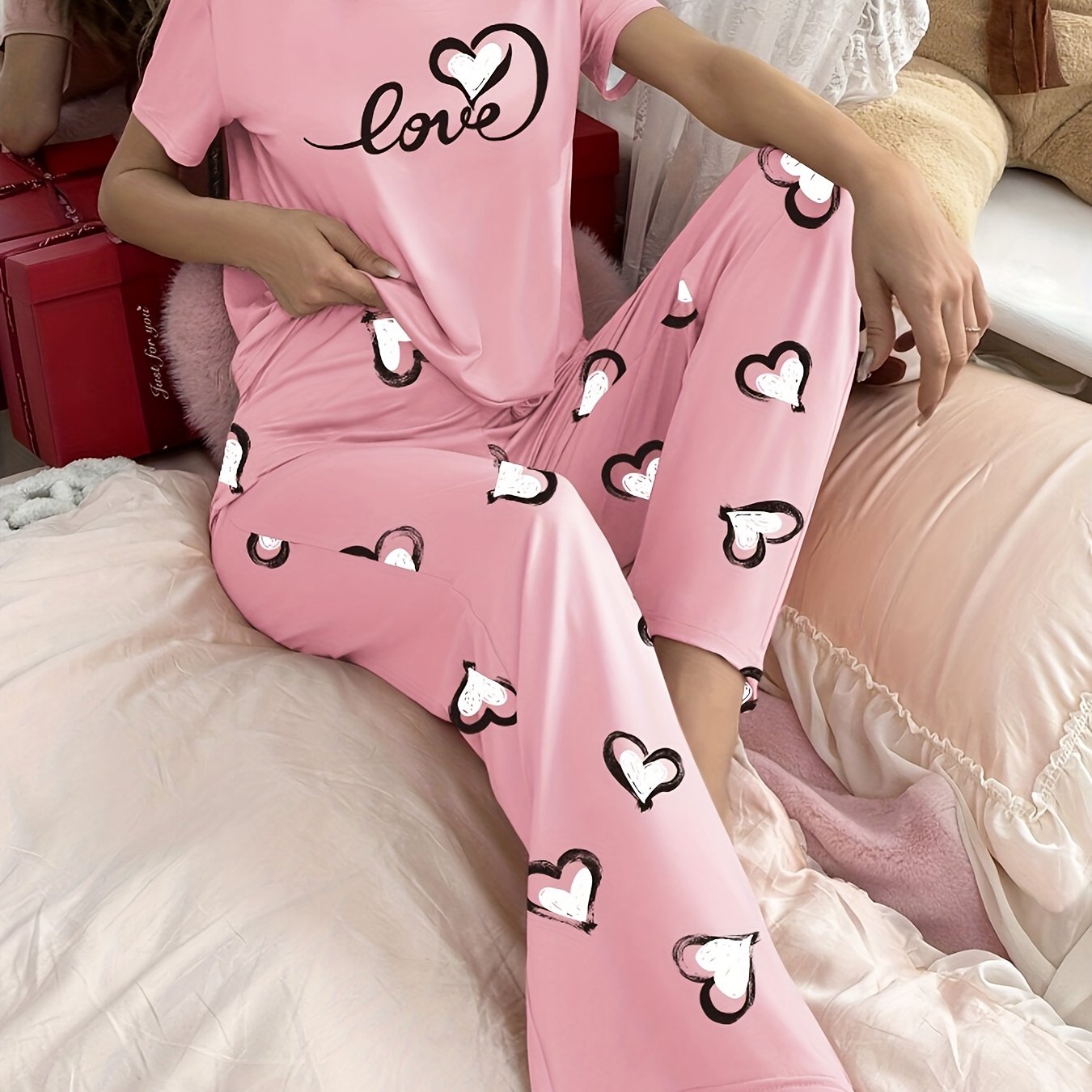 Stylish pink heart print pajama set for women with comfy short sleeve top and long pants, made of breathable polyester blend fabric.