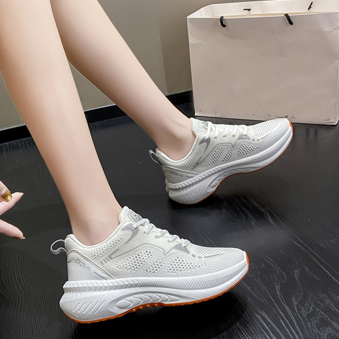 Women's low-top running shoes in white with orange sole, breathable fabric upper, rubber sole, stabilizing support, all-season casual sneakers.