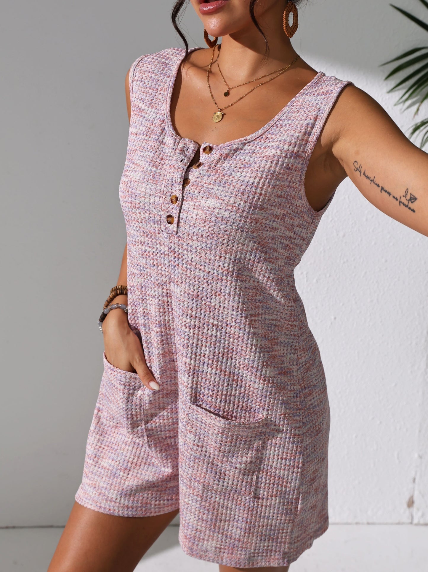 Sleeveless waffle knit romper with pockets for plus-size women in pastel pink. Comfortable and stretchy, perfect for spring/summer.