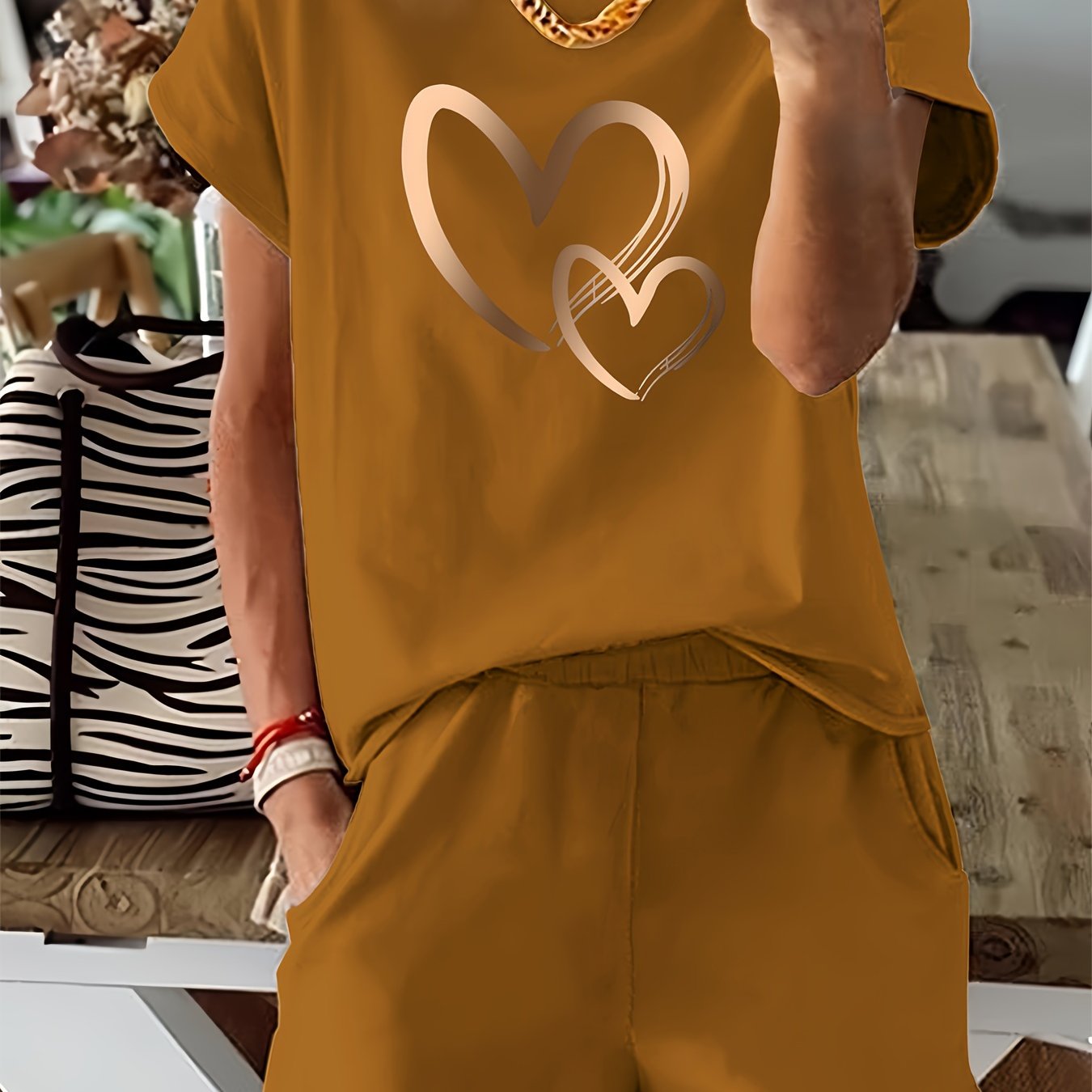 Stylish tan heart print two-piece set for women. Includes short sleeve t-shirt and high-waisted shorts. Made from soft polyester blend, machine washable. Ideal for spring/summer.