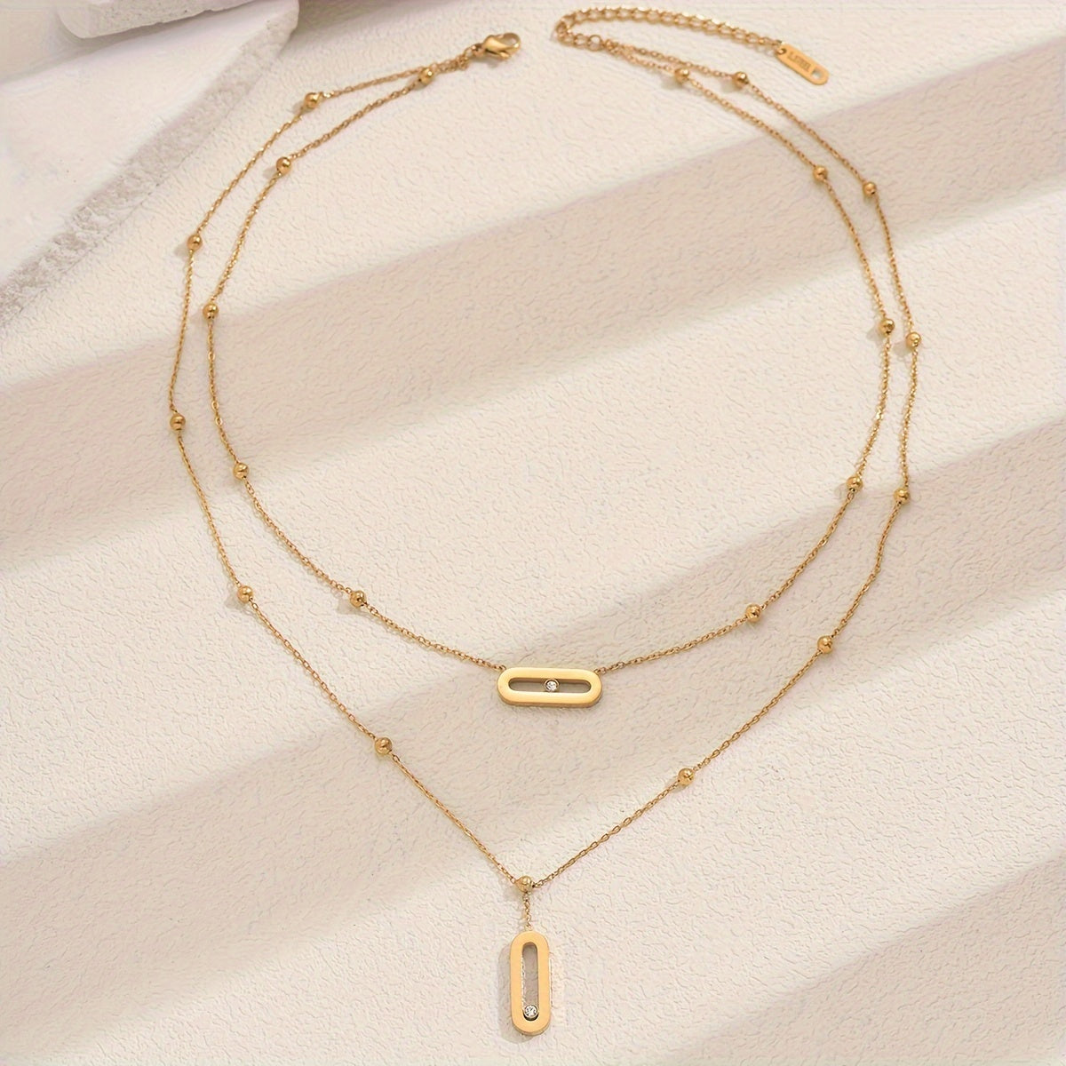 Elevate your look with this sophisticated French-inspired 18K gold plated stainless steel necklace featuring double layers and sparkling rhinestone accents. The versatile geometric pendant is perfect for women, ideal for both everyday wear and as a