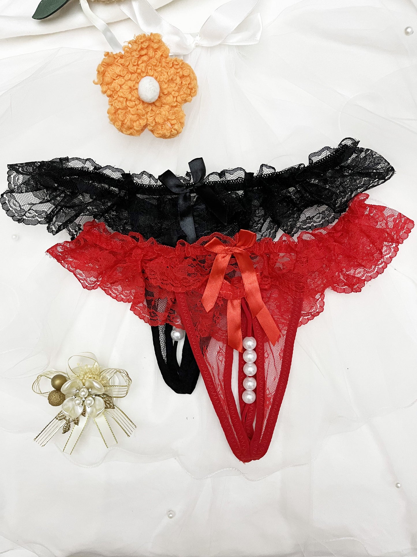 Two pack of solid color charm lace thongs with double bow and massage beaded detail.