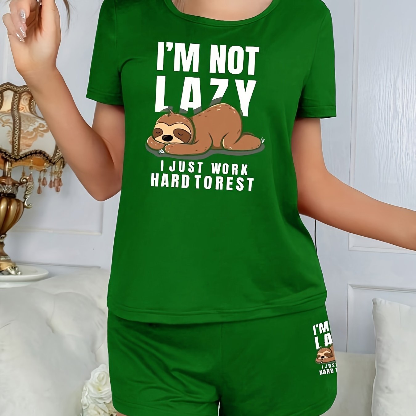 Women's sleepwear set with cute sloth print and slogan, including short sleeve top and elastic shorts.