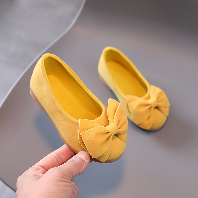 Stylish slip-on princess shoes for chic girls in pink, yellow, and black, with a bow detail. Made of comfy PU fabric with a rubber sole. Easy slip-on design for casual attire and