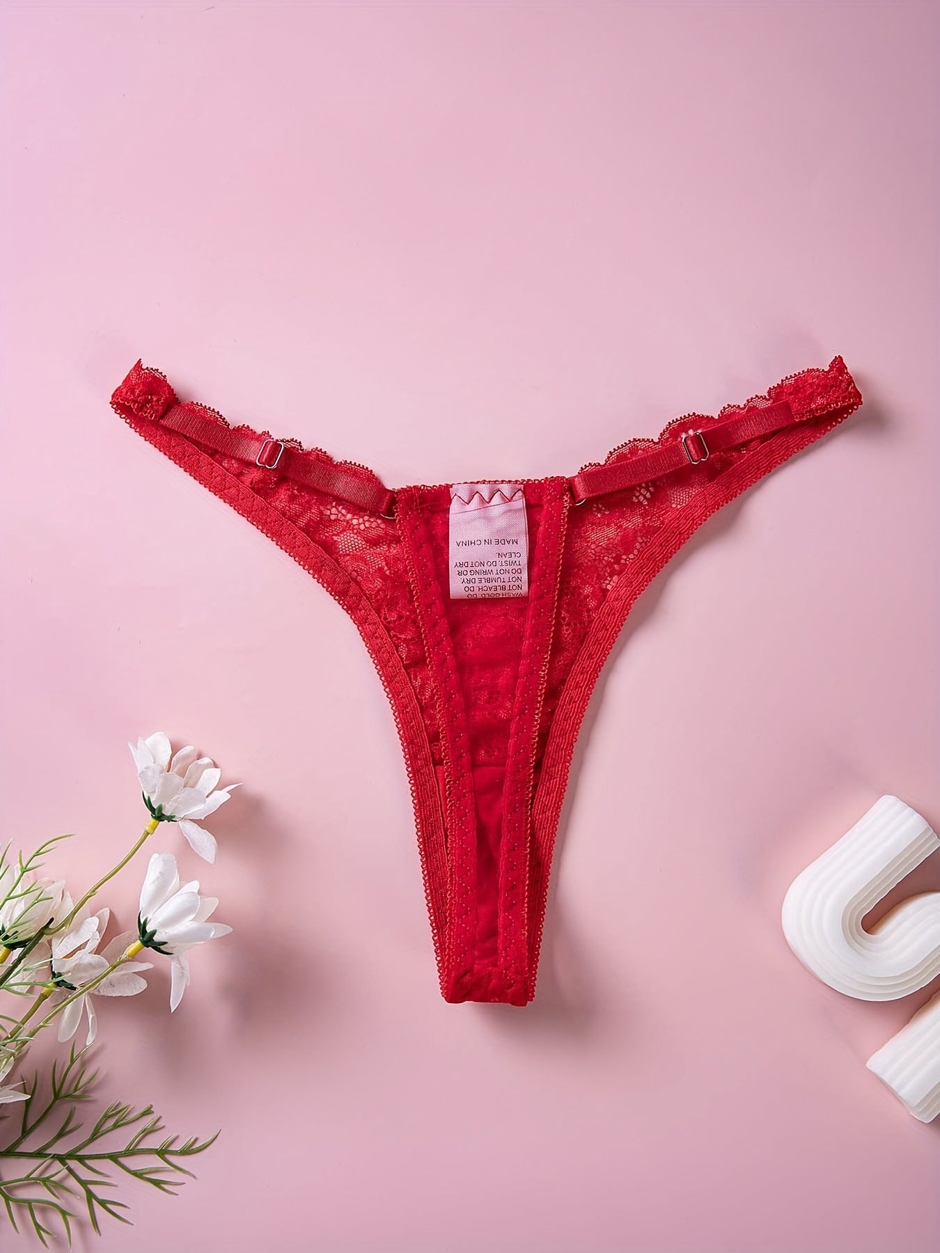 Red lace thong panties with floral print and bow detail, low rise V-shaped design. Made of breathable polyester blend, hand washable. Ideal for intimate moments.