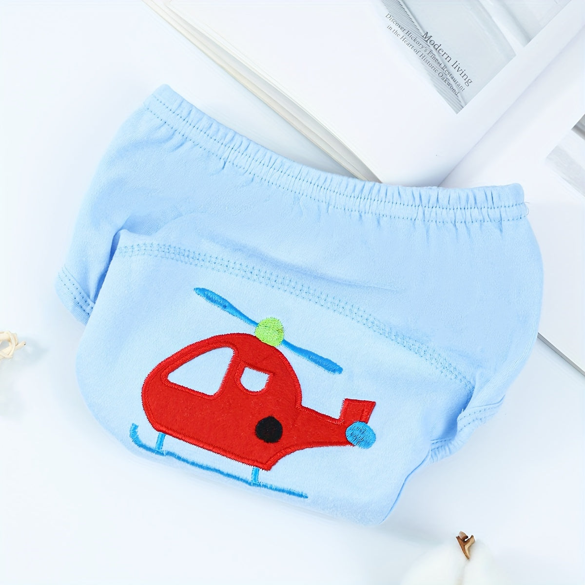 Training pants for toddlers with a fun cartoon pattern - made from 100% cotton for softness and breathability. These washable and reusable pants are highly absorbent and feature a leak-proof design, perfect for potty training essentials.