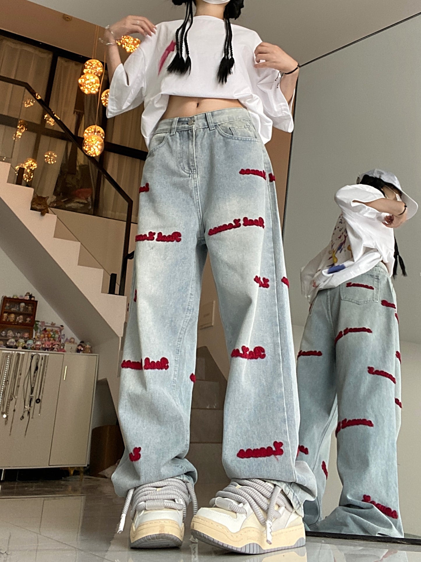 Women's denim jeans with red embroidered lettering, stretch fabric, regular fit, button closure, and washed denim detail. Casual style suitable for all seasons.