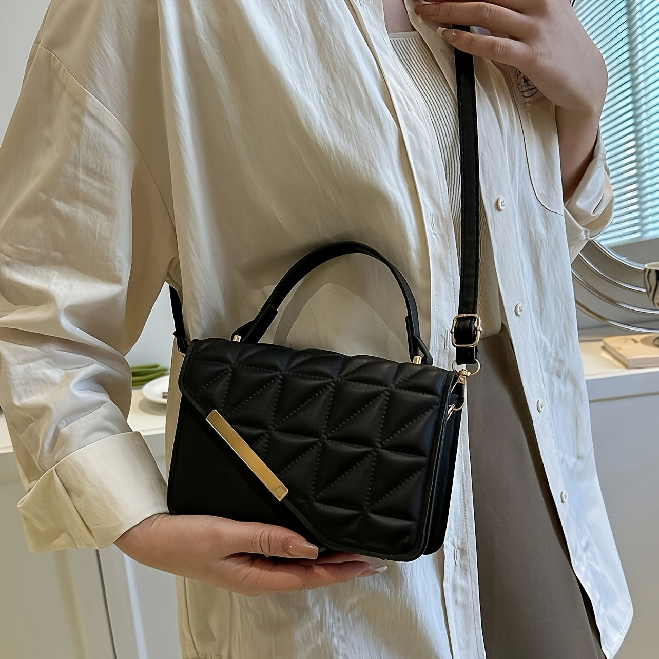 Chic black quilted crossbody bag with detachable strap, diamond stitching, golden-tone plaque. Versatile design for everyday use.