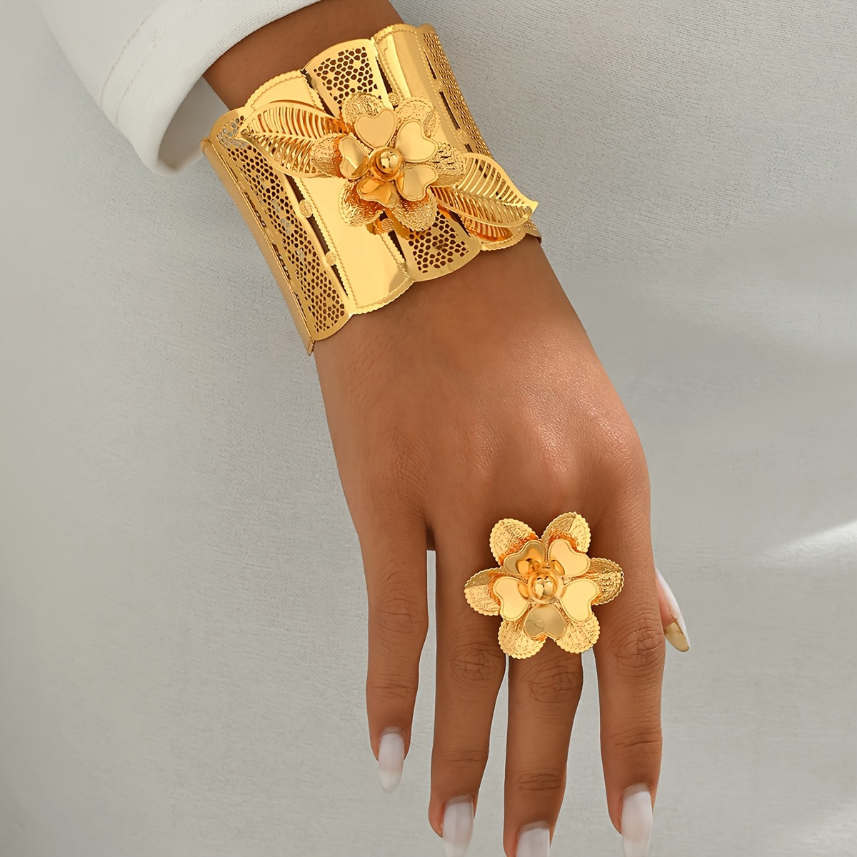 Indulge in luxury with this exquisite Women's Classic Hollow Floral Bracelet and Ring Set, perfect for both everyday wear and special occasions. This set includes a stunning 2-piece Arabic Wide Bracelet and Adjustable Ring Set, designed with intricate