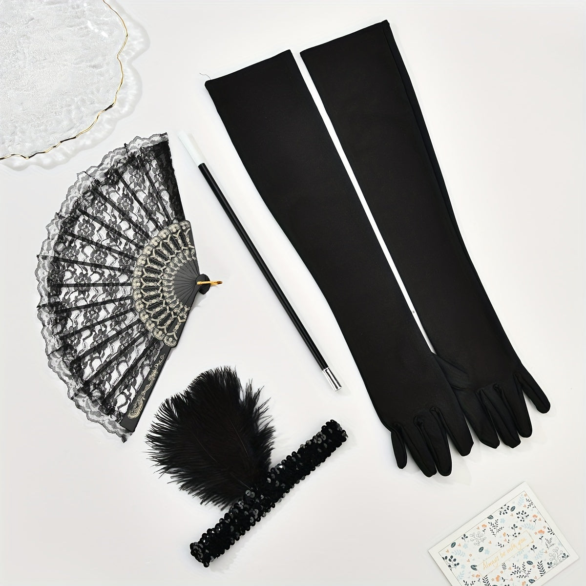 A collection of 1920s masquerade party accessories including gloves, faux feather hair clips, smoke tube fans, and other dress embellishments for women.