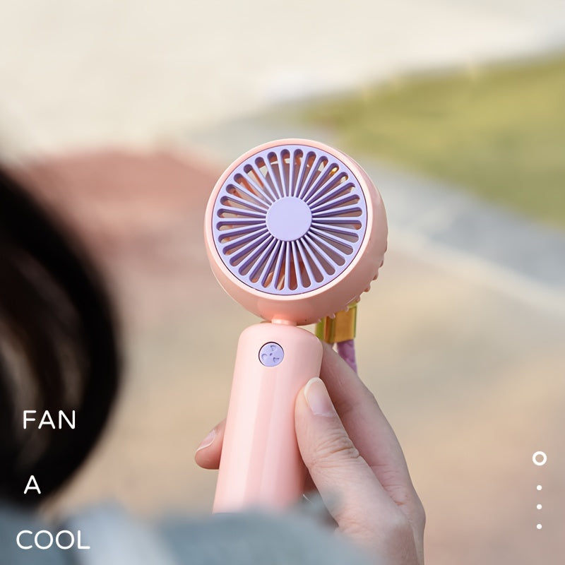 Small handheld portable fan with USB rechargeable battery, three adjustable speeds, and wearable design for use both indoors and outdoors.