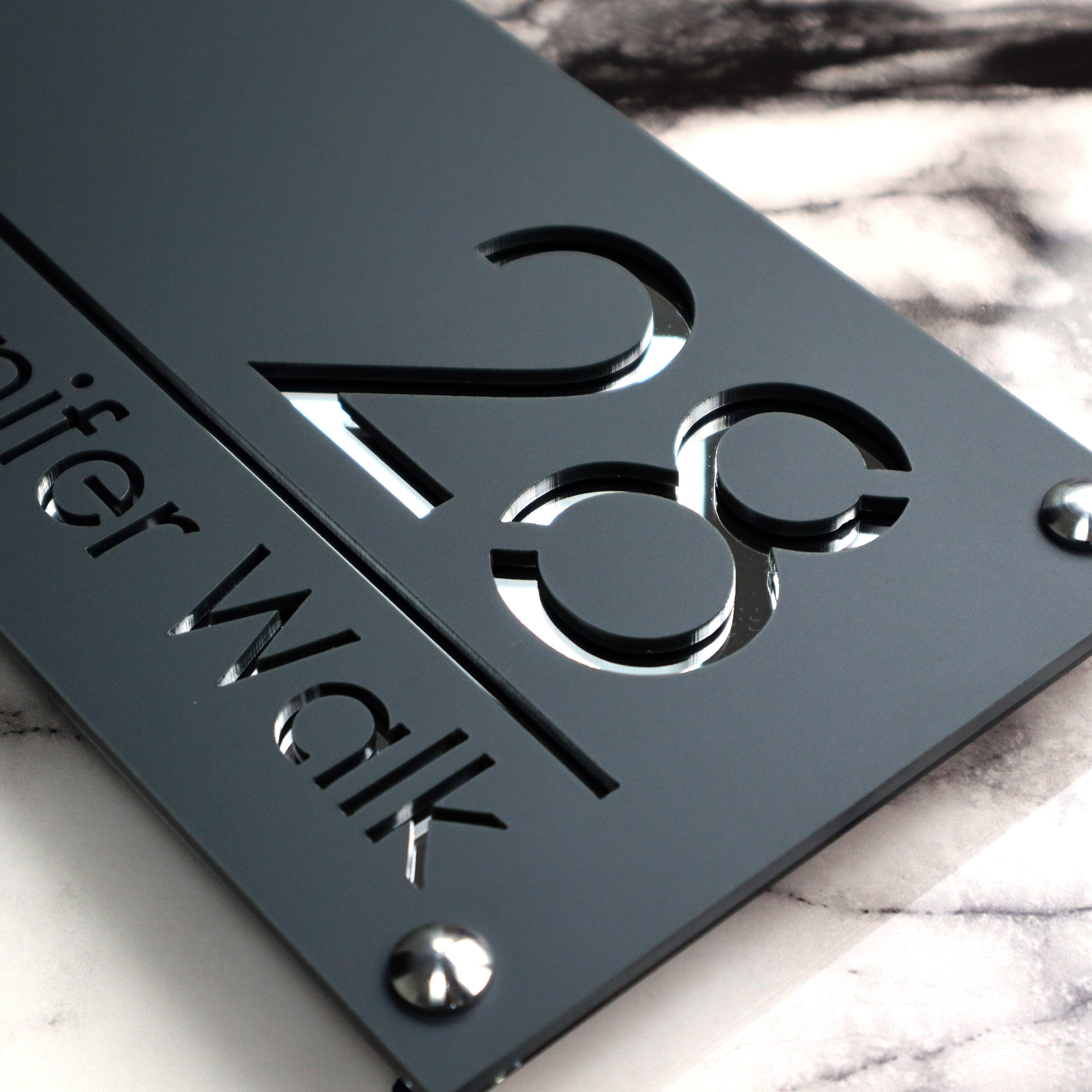 Custom British house number sign made from laser-cut acrylic with a matte gray and silvery mirror finish.