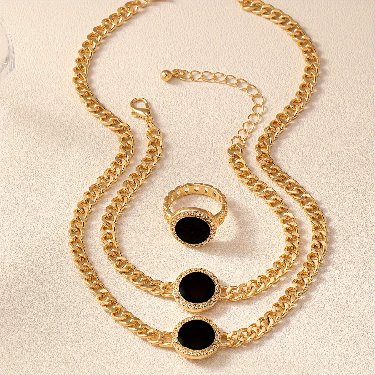 A collection of sleek and stylish black circular jewelry, including a necklace, ring, bracelet, and matching three-piece set.