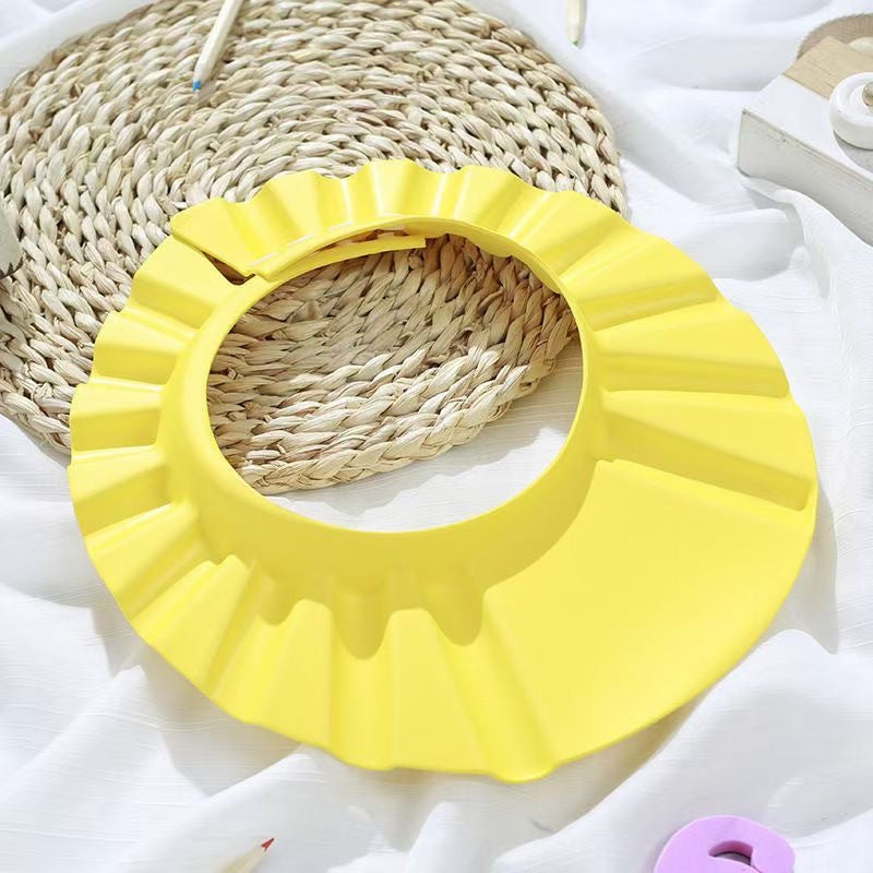 Adjustable baby shampoo cap in pink and yellow, made of soft polyester, protects eyes and ears during hair washing. Ideal for bathing and hair care.