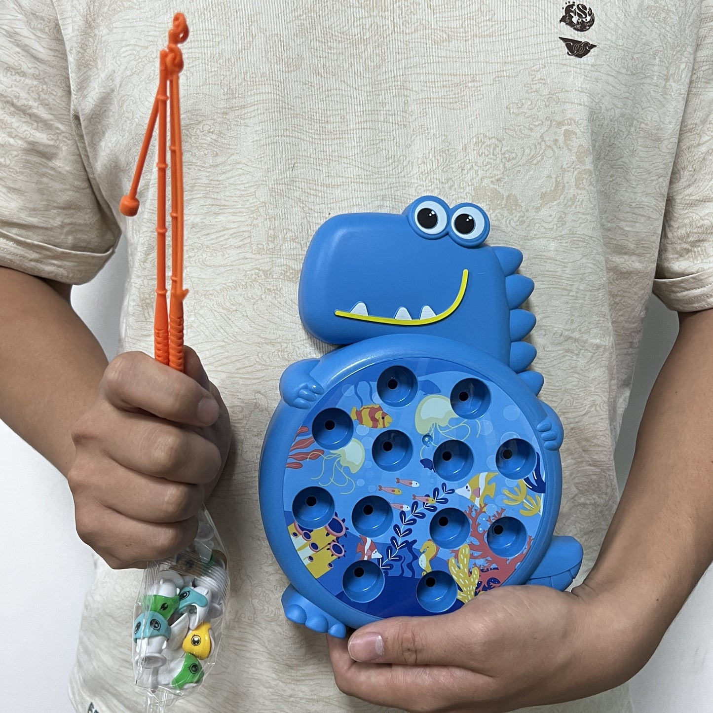 Dinosaur fishing plate toy with weak magnetic rod, suction hook, small fish, plastic material, in green/blue color.