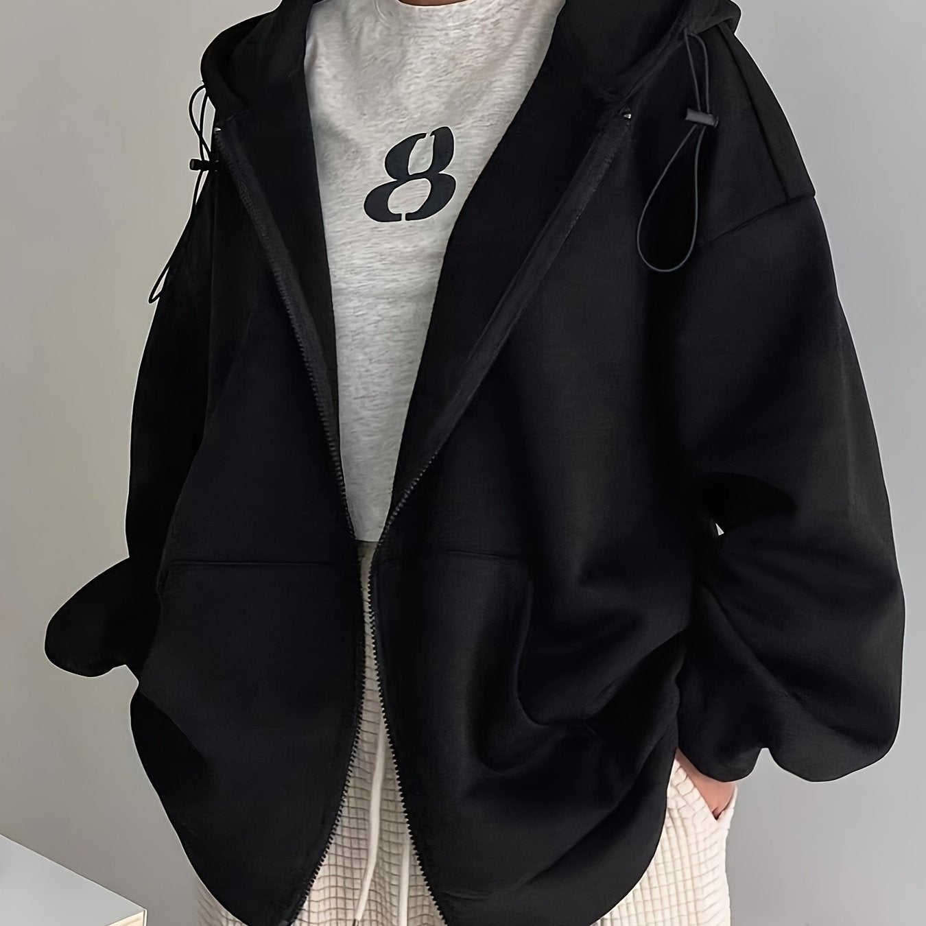 Black zip-up hoodie with fleece lining, long sleeves, loose fit, perfect for fall/winter, machine washable, features oversized hood.