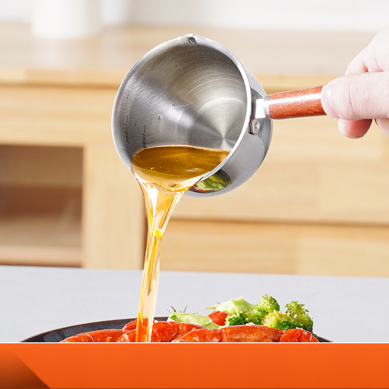 Small saucepan made of stainless steel with a wooden handle, perfect for pouring hot oil or serving soup and sauce, featuring a measuring spout for accuracy.