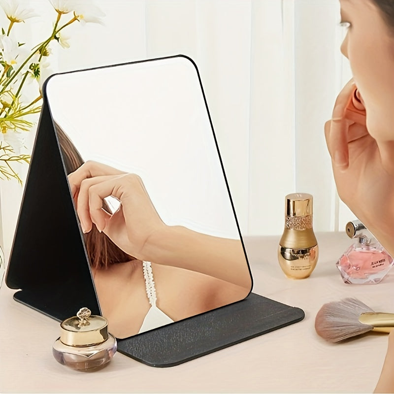 Stylish black foldable makeup mirror, great for desk, bedroom, and bathroom decor. Ideal for travel and makes a unique gift for weddings, parties, and birthdays. Glass surface with polished finish.