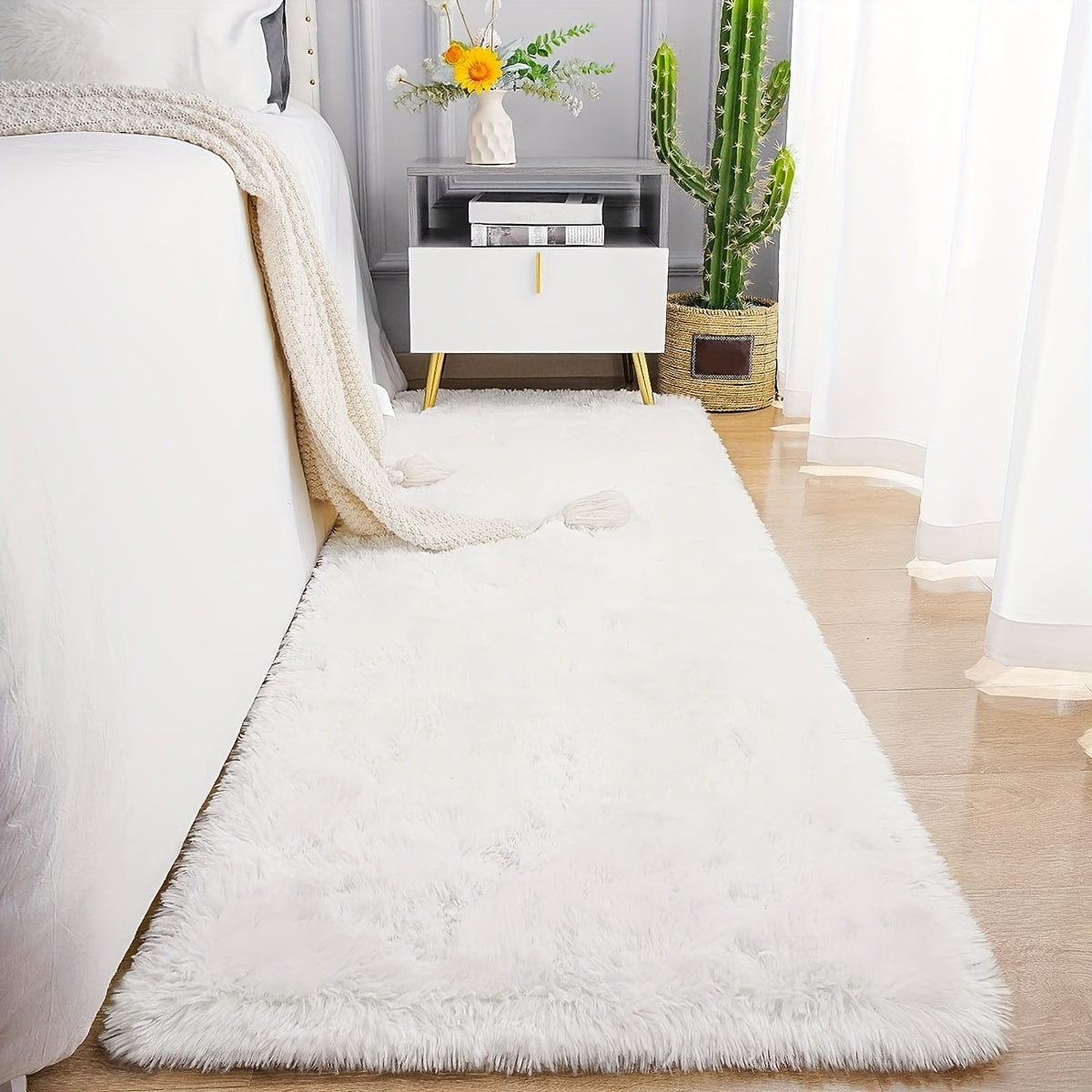 Cozy and luxurious soft white faux fur area rug, featuring a rectangle shape with non-slip backing and stain-resistant properties. This fluffy rug adds a touch of warmth and texture to any bedroom or living room, perfect for indoor use. Made of polyester