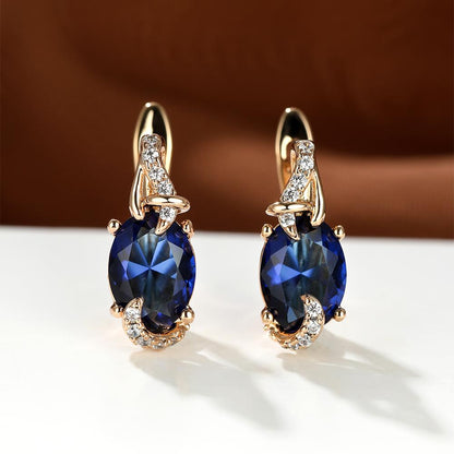 Trendy women's earrings featuring blue, white, red, and pink stones in round and oval cuts. These anniversary claw earrings are plated with 18K gold. Perfect for adding a pop of color to any outfit.