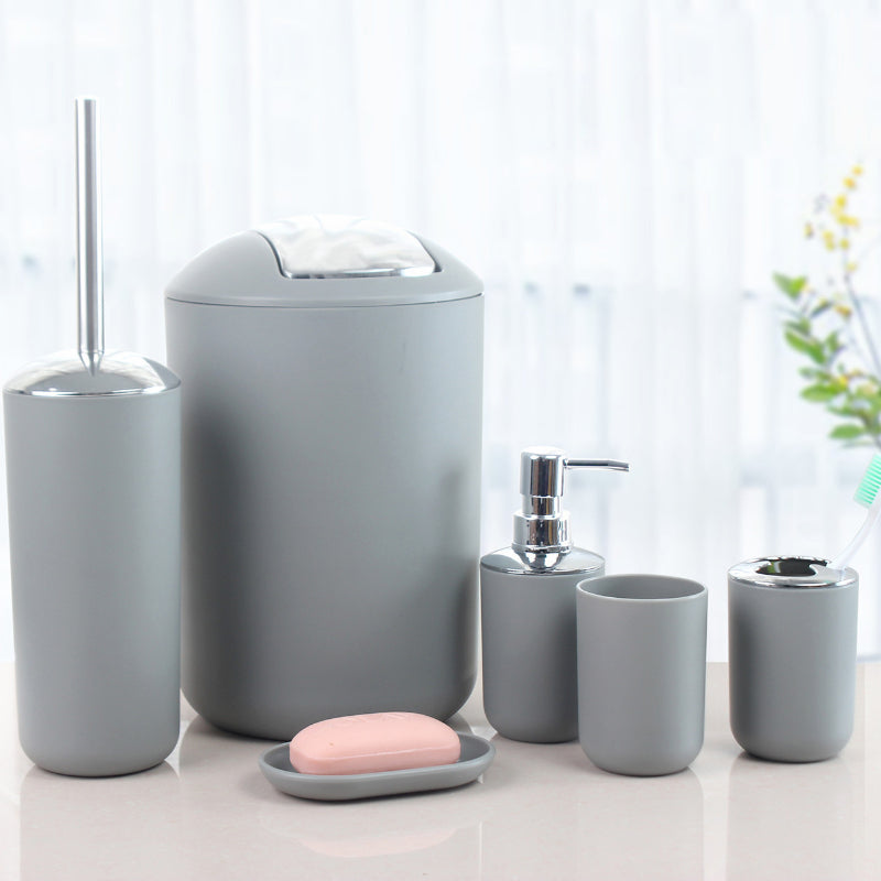 Plastic bathroom accessory set includes soap dispenser, toothbrush holder, toilet brush, trash can, tumbler, and soap dish.