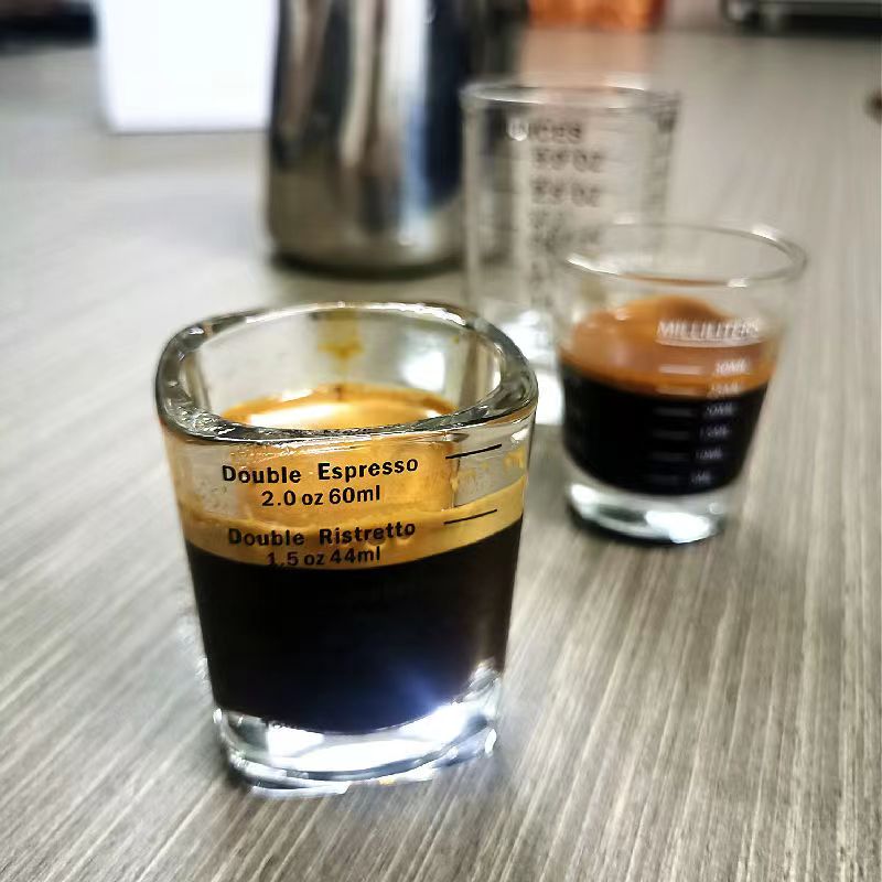 Ikkita espresso o'lchov stakanlari, qalin shishadan tayyorlangan, issiqqa chidamli, aniq qahva qovurish va tayyorlash uchun o'lchov untsiyalari bilan, kvadrat shaklda, konsentratsiyalangan.