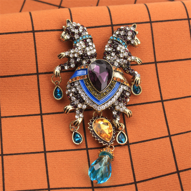 Luxurious and elegant, this animal brooch pin featuring a double-headed leopard with tassel is adorned with rhinestones. This novelty accessory has an irregular shape that enhances its charm. Perfect for adding a decorative touch to clothing, bags, and