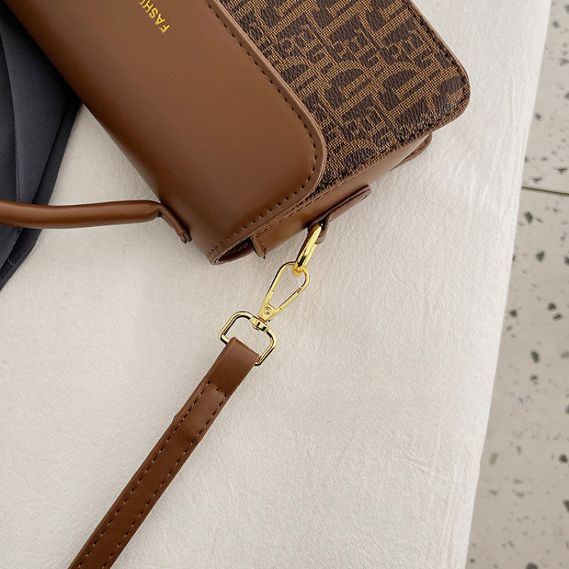 Stylish crossbody bag with letter print, adjustable strap, black & golden accents, perfect for everyday use. Chic fashion accessory with magnetic closure.