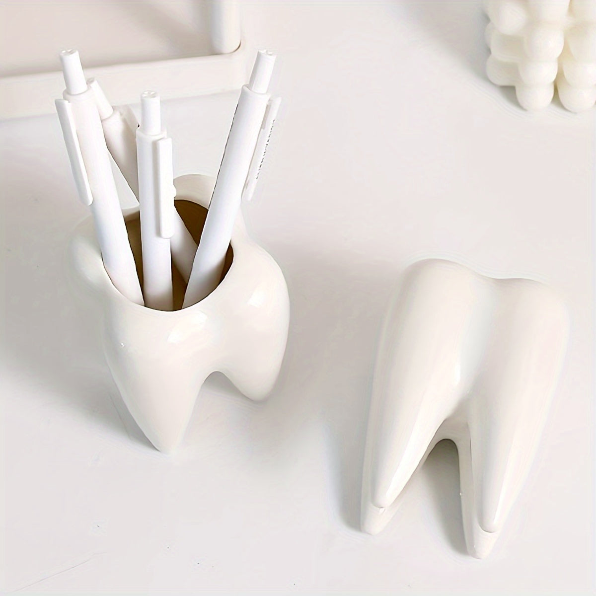 Tooth-shaped ceramic pen holder for desk or bathroom storage.