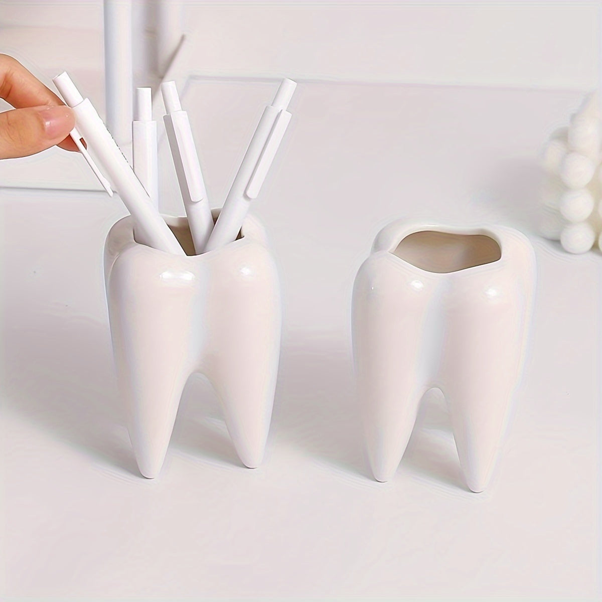 Tooth-shaped ceramic pen holder for desk or bathroom storage.