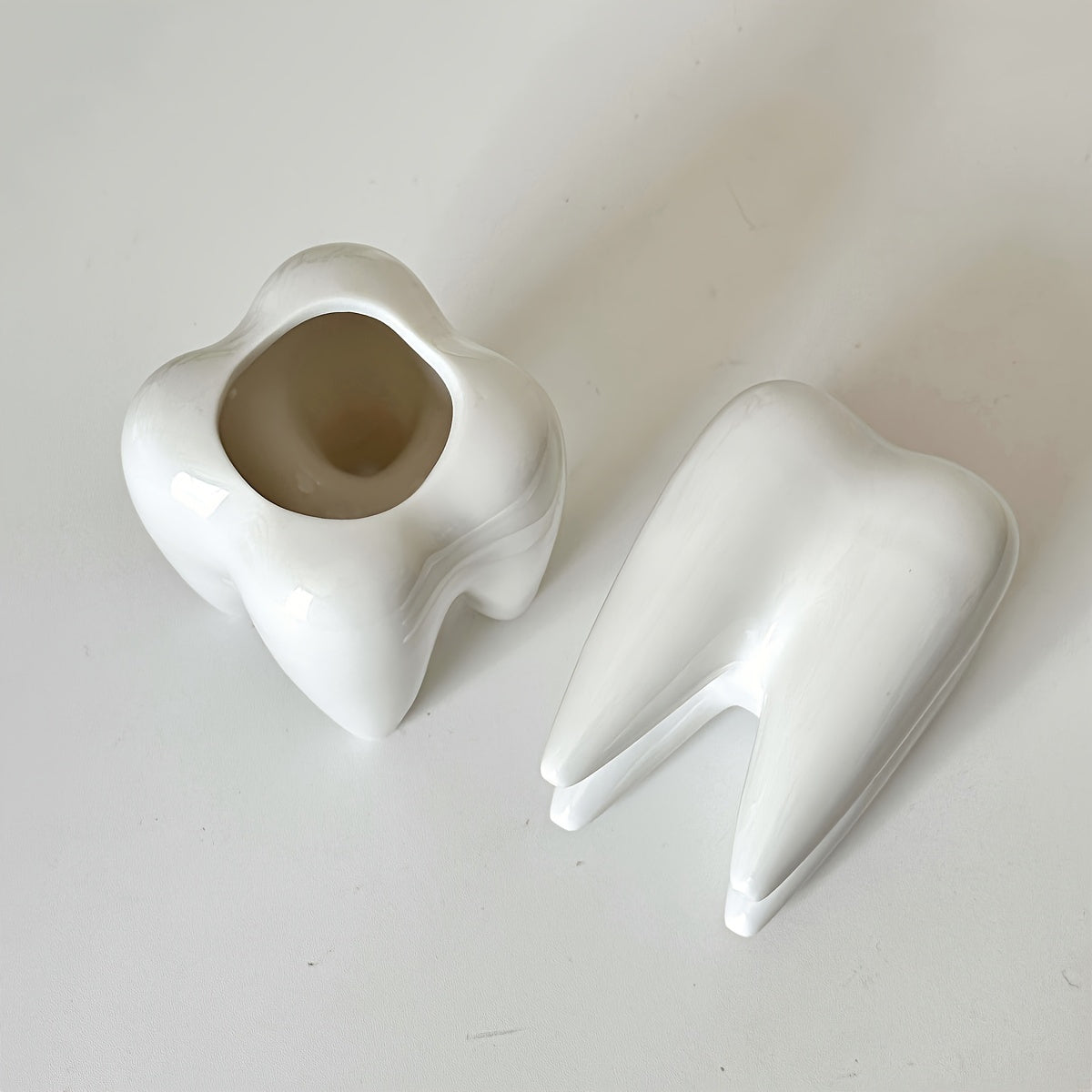 Tooth-shaped ceramic pen holder for desk or bathroom storage.