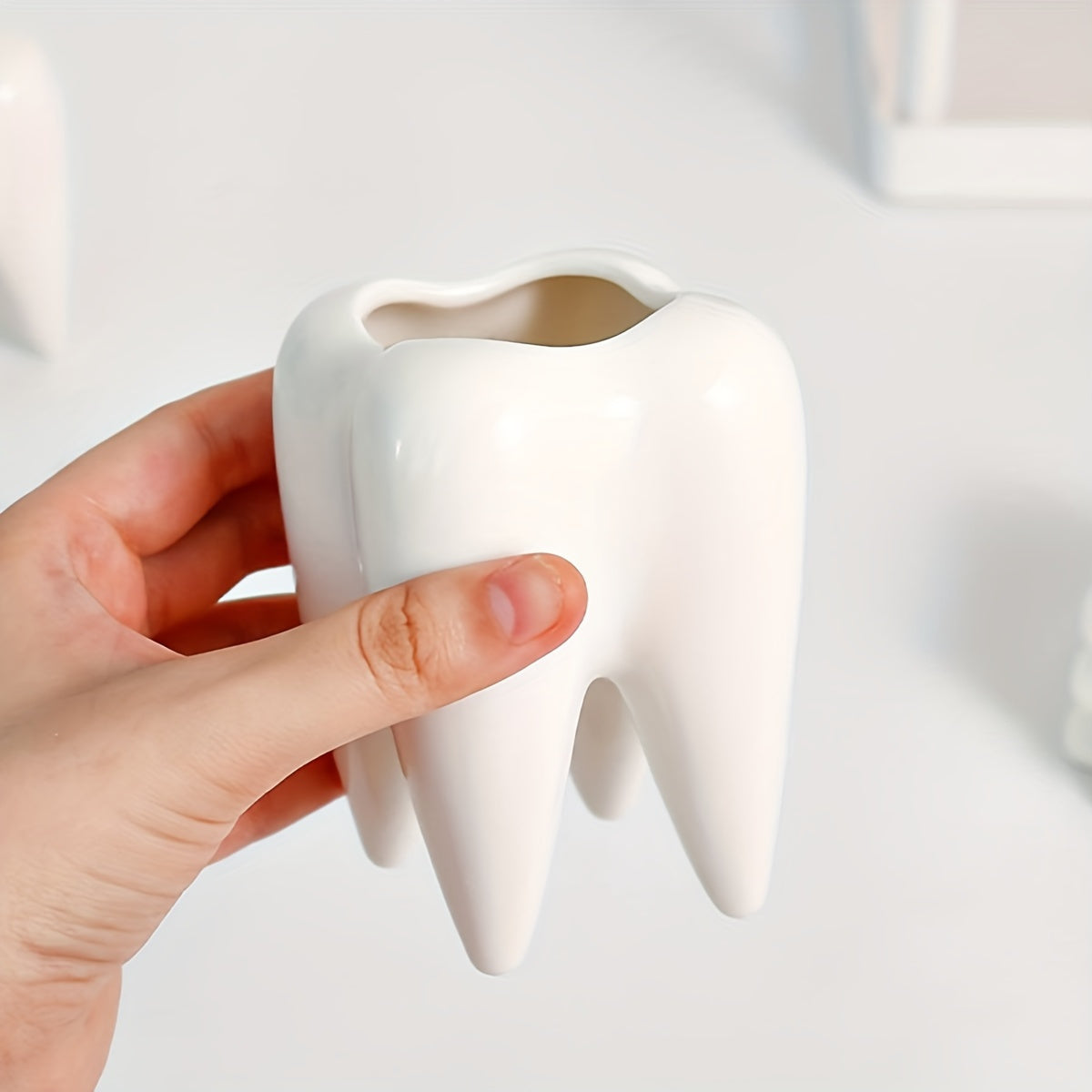 Tooth-shaped ceramic pen holder for desk or bathroom storage.