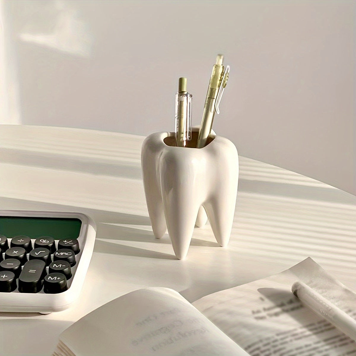 Tooth-shaped ceramic pen holder for desk or bathroom storage.