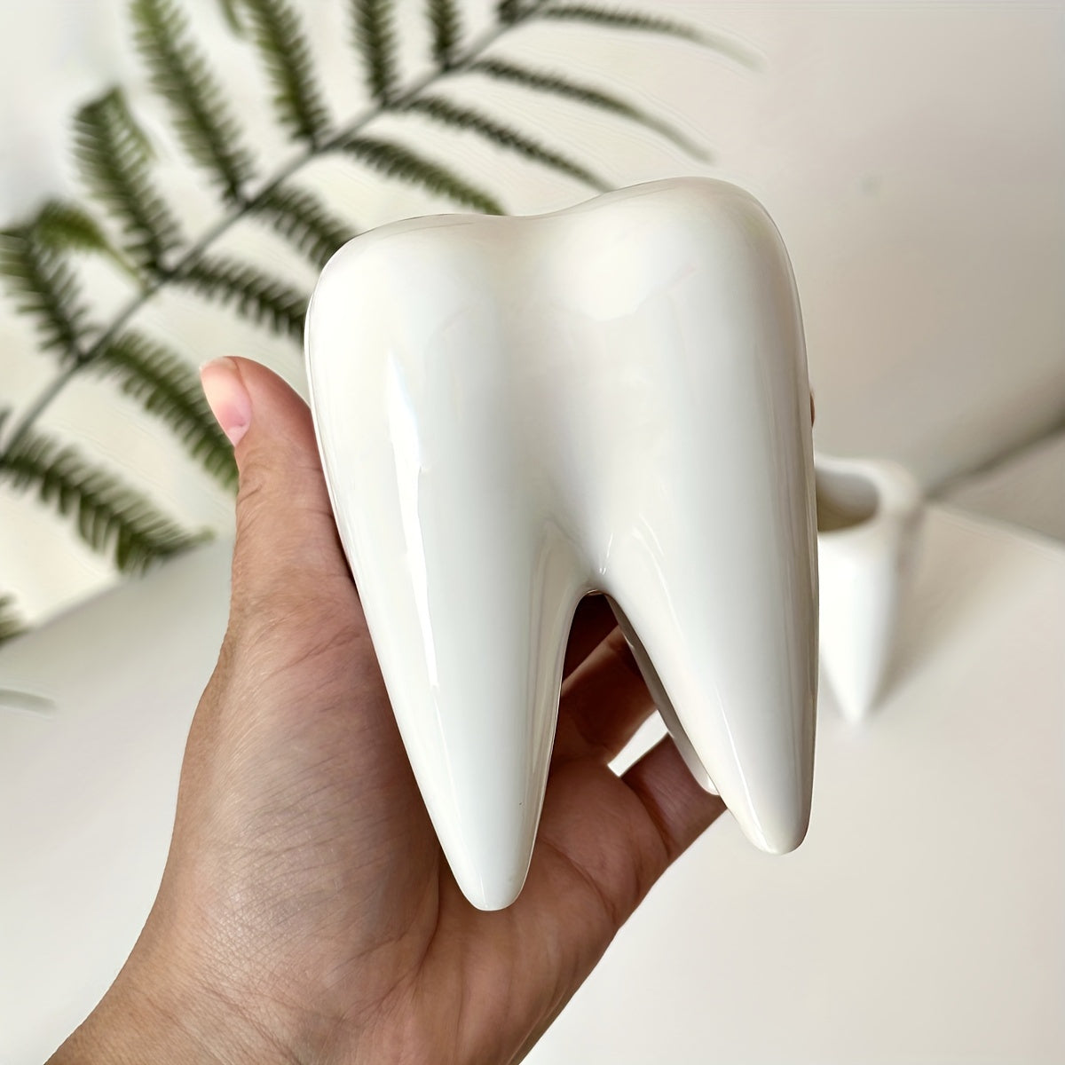 Tooth-shaped ceramic pen holder for desk or bathroom storage.