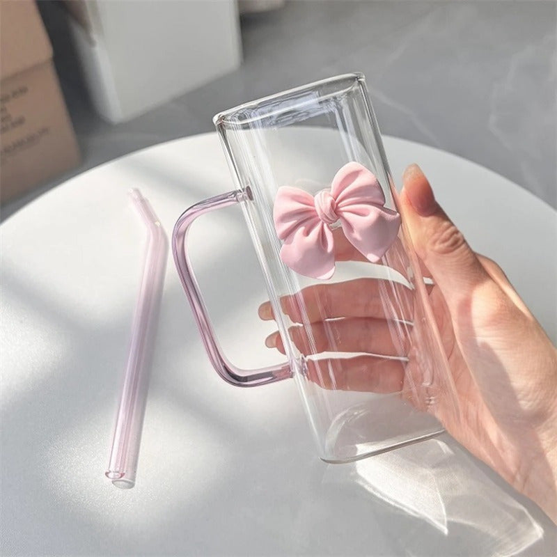 Clear Glass Mug with Handle features a bow decoration on a square drinking cup. This high-temperature resistant mug comes with a straw, perfect for enjoying coffee, milk, or water. Ideal for use at home, in the kitchen, or at parties.