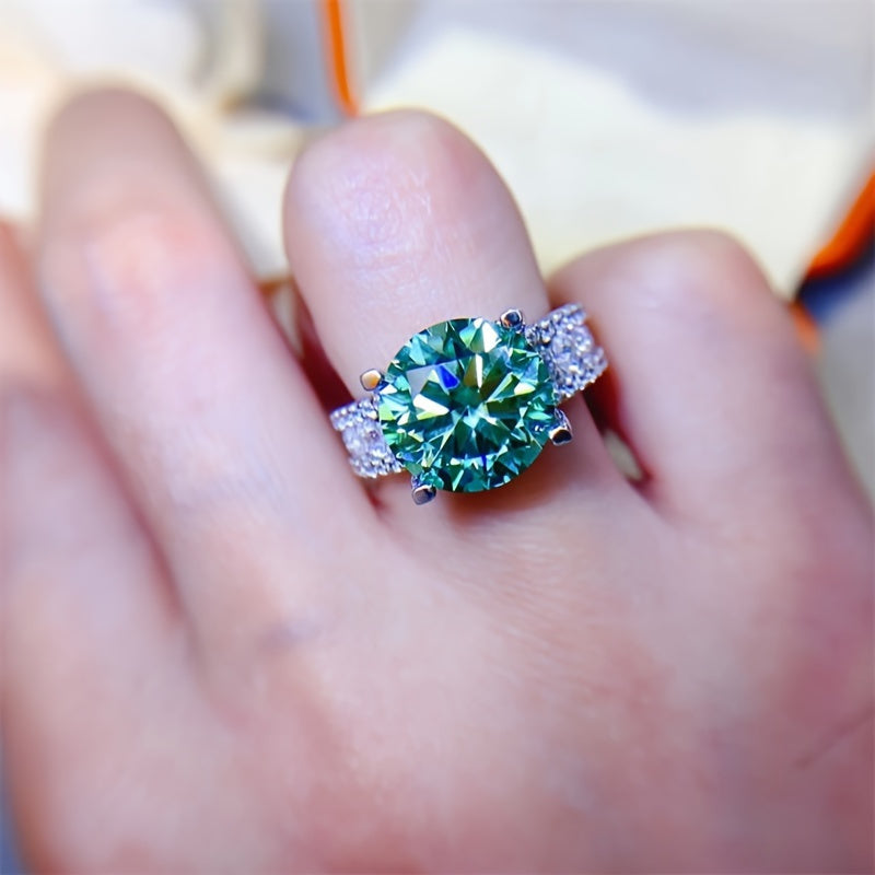 The 925 sterling silver promise ring features an elegant 10ct blue-green Moissanite stone in a 4-prong setting. It is hypoallergenic and coated with 18K golden plating, making it an ideal choice for daily wear or as a gift for Valentine's Day. This ring