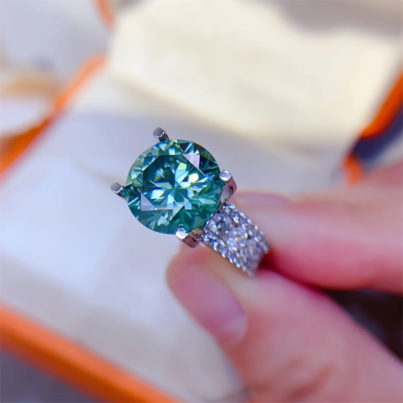 The 925 sterling silver promise ring features an elegant 10ct blue-green Moissanite stone in a 4-prong setting. It is hypoallergenic and coated with 18K golden plating, making it an ideal choice for daily wear or as a gift for Valentine's Day. This ring