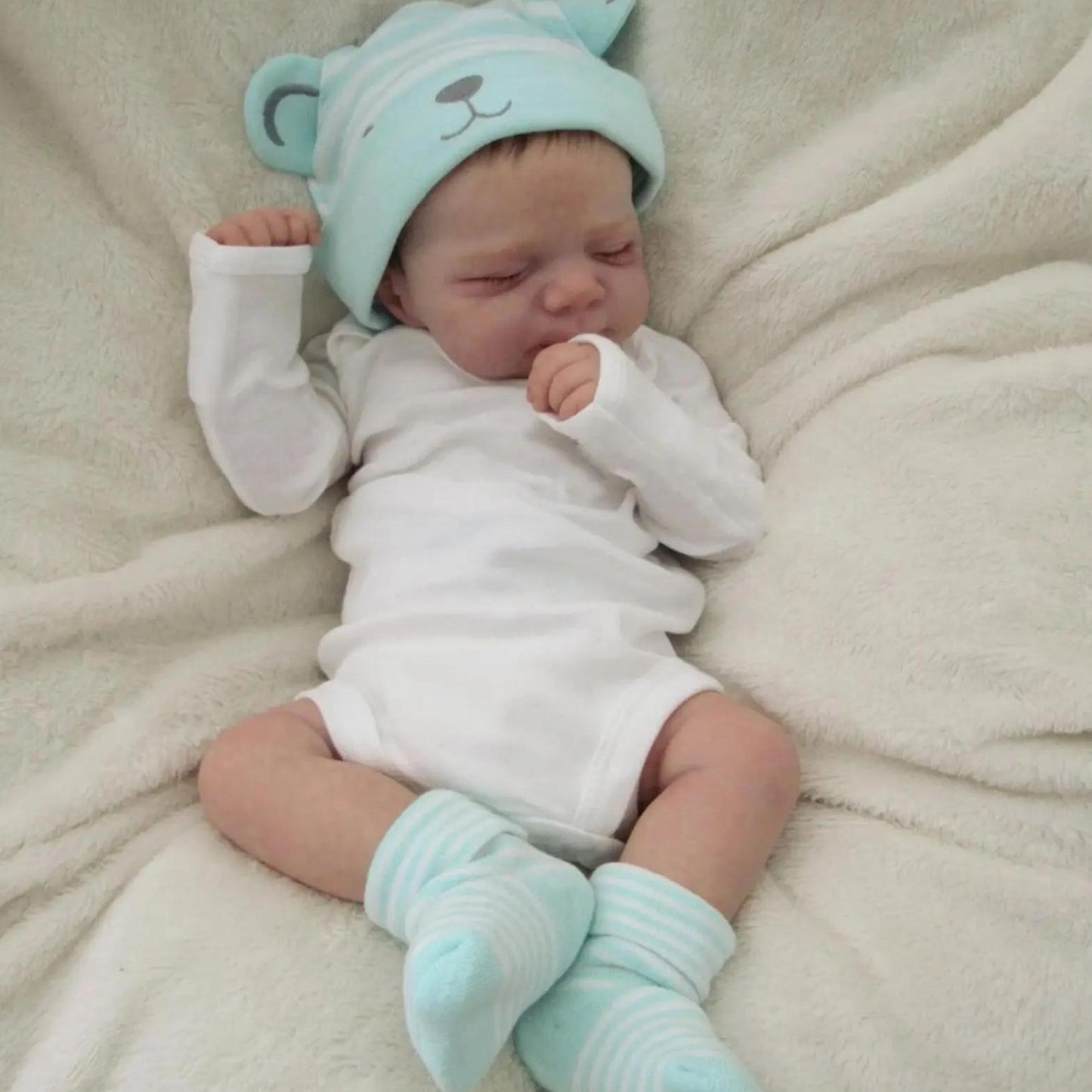 Realistic 18-inch reborn girl doll with blue bear hat, soft vinyl body, detailed skin, visible veins, and lifelike sleeping pose. Ideal birthday gift for children 3 and up.