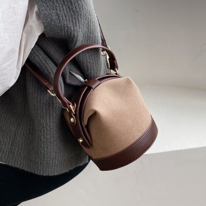 Fashionable women's bucket bag in two-tone brown and beige with gold hardware, ideal for travel and everyday use. Modern tote bag option.