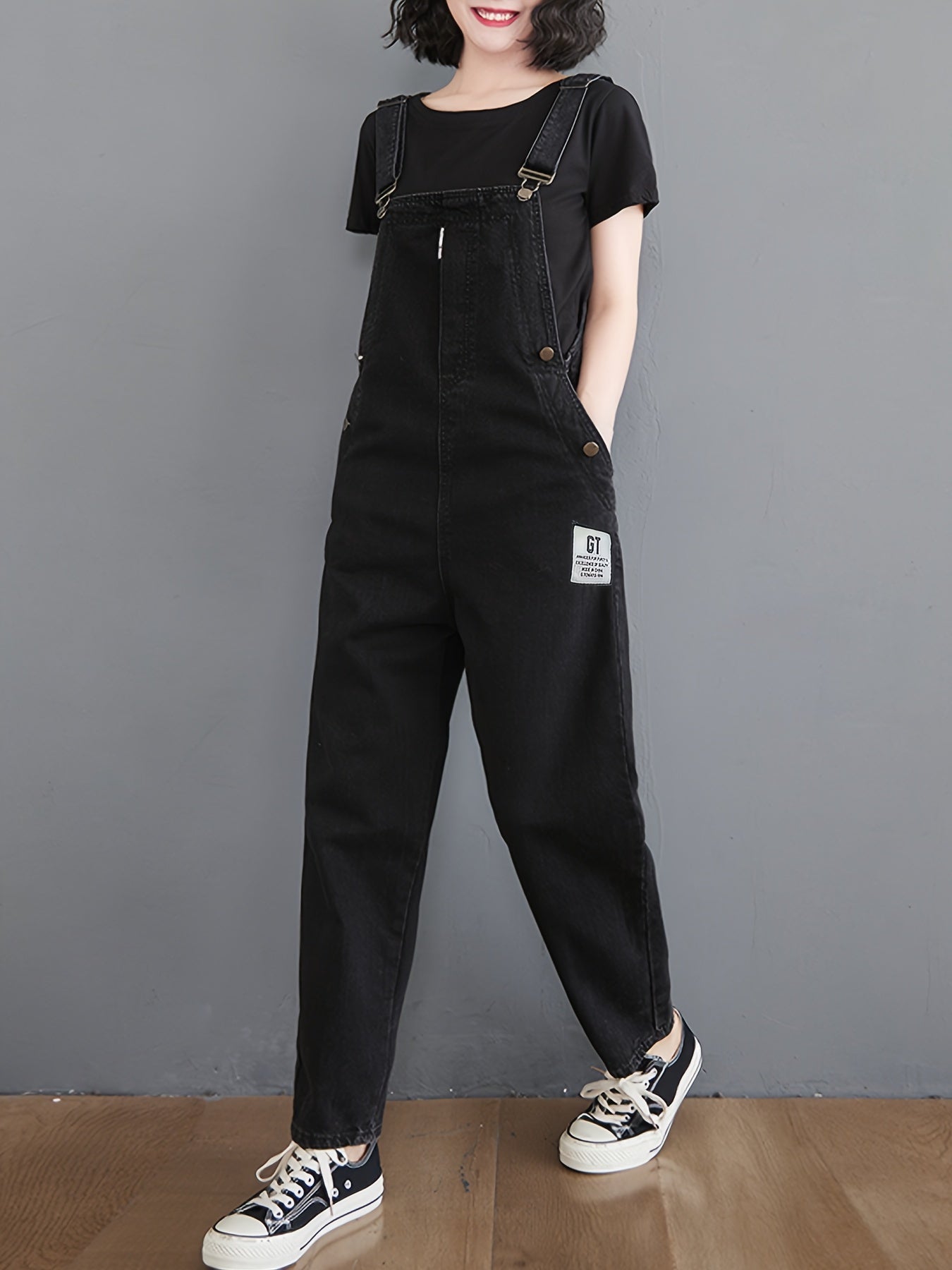 Classic black denim overalls for women with adjustable straps, loose fit, slant pockets and harem hem in non-stretch fabric for all-season wear.