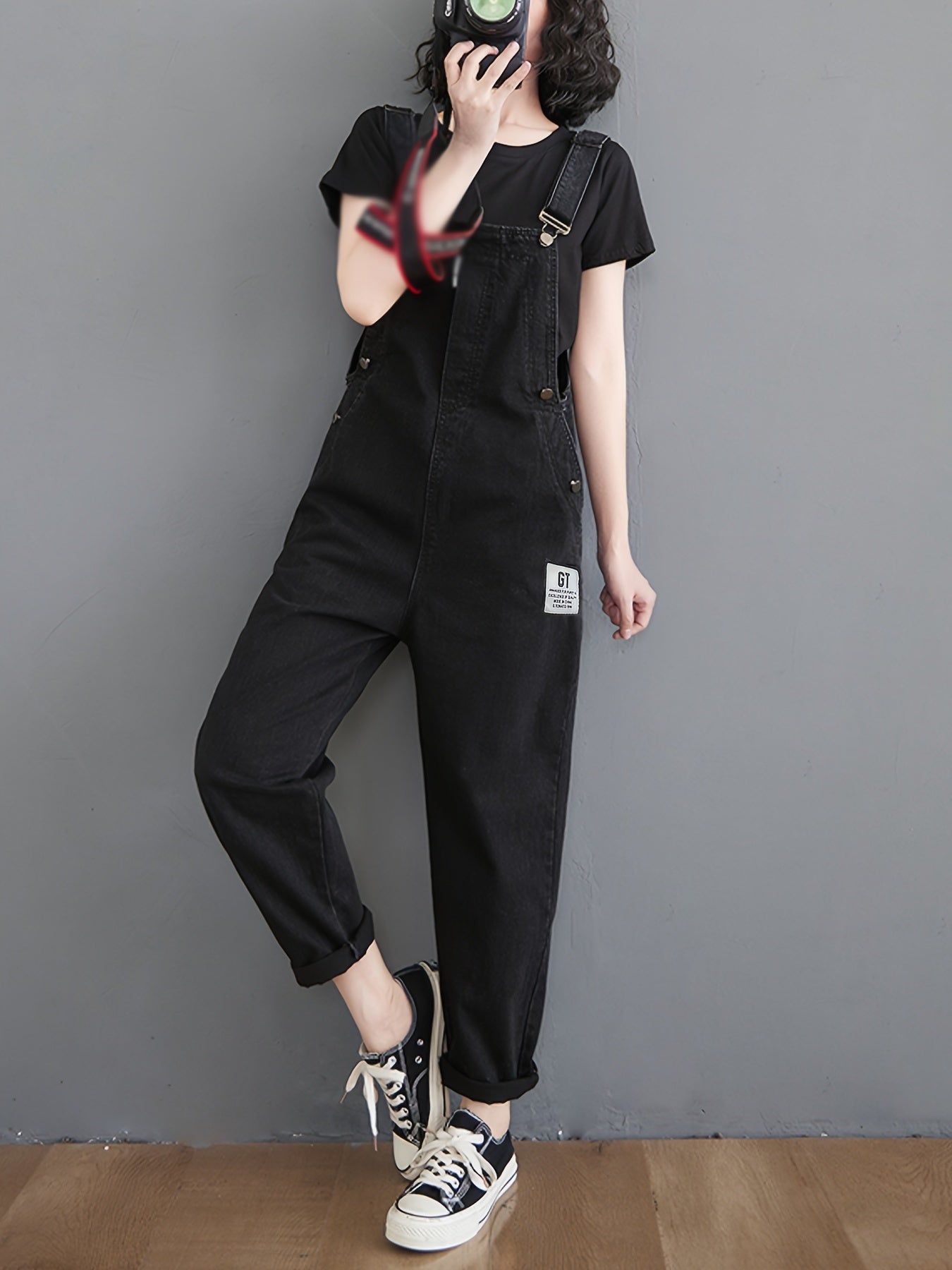 Classic black denim overalls for women with adjustable straps, loose fit, slant pockets and harem hem in non-stretch fabric for all-season wear.