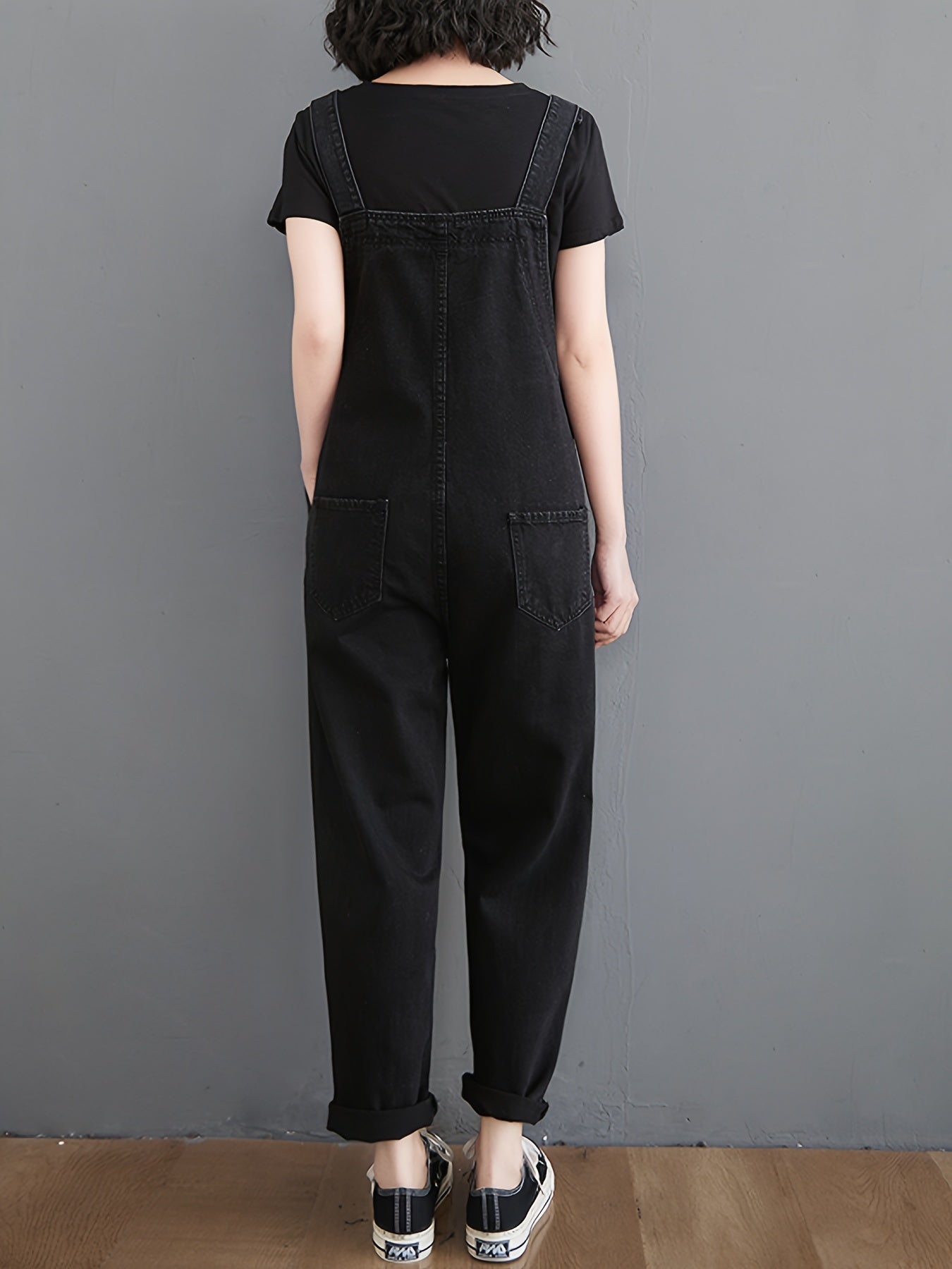 Classic black denim overalls for women with adjustable straps, loose fit, slant pockets and harem hem in non-stretch fabric for all-season wear.