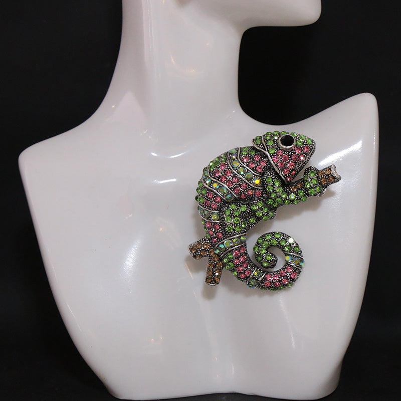 This stylish brooch pin features luxurious rhinestones and is designed in an elegant chameleon shape. The fashionable green and pink crystals adorn the piece, creating a unique and irregular shape. This versatile accessory can be worn as chest jewelry or