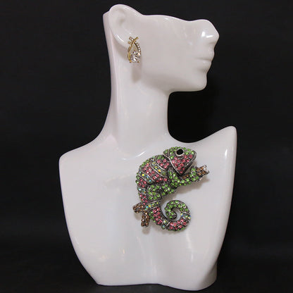 This stylish brooch pin features luxurious rhinestones and is designed in an elegant chameleon shape. The fashionable green and pink crystals adorn the piece, creating a unique and irregular shape. This versatile accessory can be worn as chest jewelry or