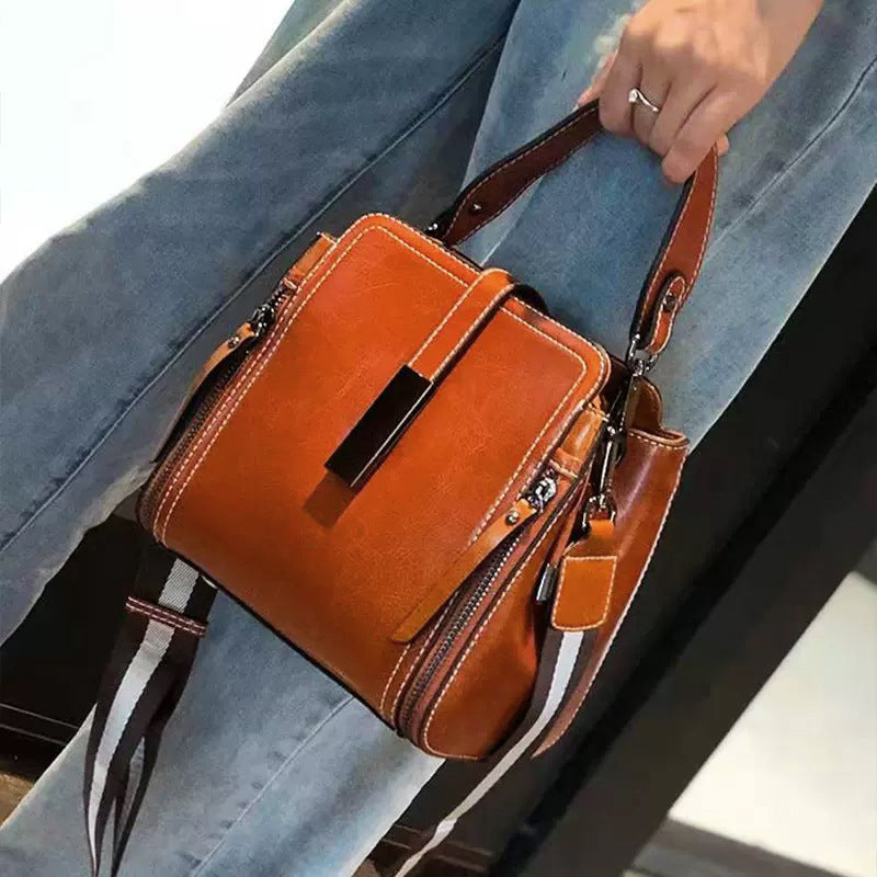 Stylish leather shoulder bag for women with removable strap, zipper closure, and edge paint detail. Available in black, coffee, and light brown.